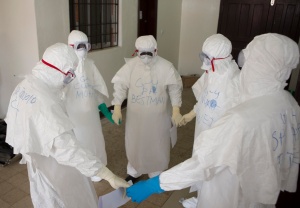 Health workers wearing protective equipment hold hands as they pray at the start of their shift before entering the Ebola treatment center in Monrovia, Liberia, Sept.30. Joe Sehnert, a member of Ascension Parish in Chesterfield, Mo., is helping the local community cope with the Ebola outbreak as a lay missionary with Liberia Mission, an effort of Franciscan Works. (CNS photo/Christopher Black, WHO, Handout via Reuters) 